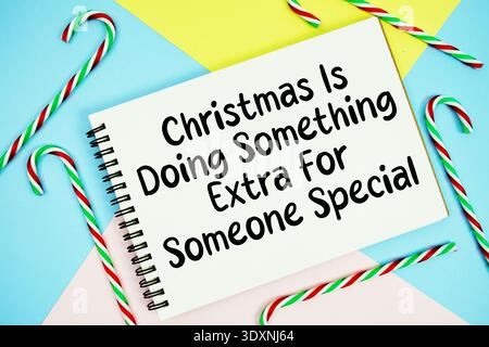 Weihnachten macht etwas Besonderes für jemand Besondere Botschaft der Feiertage auf Notizblock mit Zuckerrohr Dekoration auf pastellfarbenem Hintergrund Stockfoto