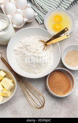 Verschiedene Schüsseln mit Mehl, Eiern, Zucker, Hefe, Butter, und Milch zum Backen Stockfoto