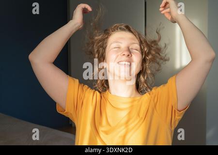 Glückliche Frau, die mit erhobenen Armen tanzt und Freude ausdrückt Stockfoto