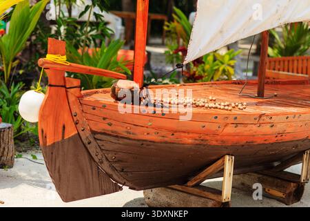 Handgefertigte Holzboote stehen auf der Ausstellung. Reich gebeiztes Holz zeigt detailgetreue Handwerkskunst. Das weiße Segel lehnt sich sanft gegen den Mast. Grobseil und Stockfoto