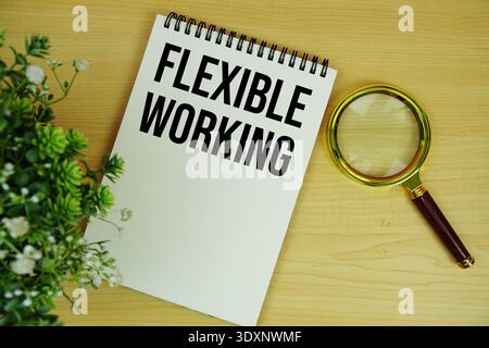 Flexibler Arbeitstext auf Notizblock mit Lupe flach auf hölzernem Hintergrund Stockfoto