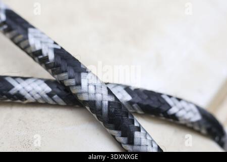 Nahaufnahme eines starken schwarz-weißen geflochtenen Seils. Kompliziertes Webmuster und Textur aus synthetischer Faser schaffen einen modernen und abstrakten Hintergrund Stockfoto