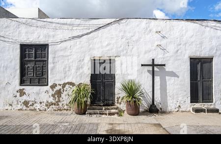 Typisches weißes Haus mit Holztüren und Fenstern in einer Gasse mit vulkanischem Krater auf der Rückseite, Teguise, Lanzarote, Kanarische Inseln, Spanien Stockfoto