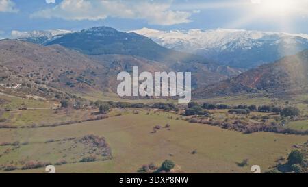 Sonniger Panoramablick auf die Berge der Sierra Nevada in Spanien mit schneebedeckten Gipfeln, sanften grünen Hügeln, felsigen Hängen, heller Himmel, landschaftlich reizvoller andalusischer Landschaft Stockfoto