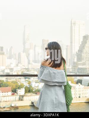 Bangkok, Thailand - 11. februar, 2024: kaukasierin Touristen Genießen Sie Shopping Mall Blick aus berühmten Aussichtspunkt über den Fluss an sonnigen heißen Tagen im Südosten Stockfoto