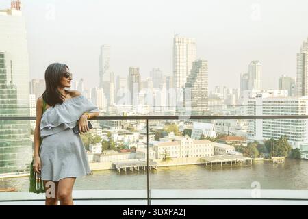 Bangkok, Thailand - 11. februar, 2024: kaukasierin Touristen Genießen Sie Shopping Mall Blick aus berühmten Aussichtspunkt über den Fluss an sonnigen heißen Tagen im Südosten Stockfoto
