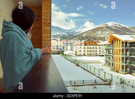 Bakuriani, Georgien - 5.. März 2022: Weibliche kaukasische Touristen am Morgen trinken Kaffee auf dem Balkon in Ferienwohnung Gebäude auf Bakuriani Urlaub s Stockfoto