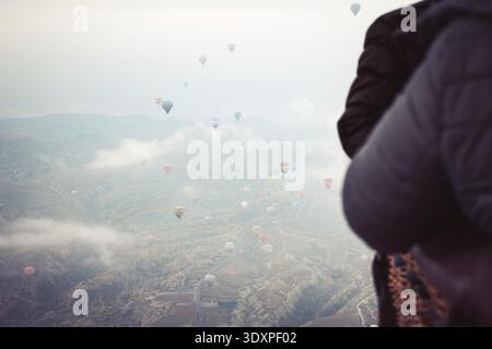 Passagiere mit Heißluftballon genießen im Winter den Blick auf die Kapadokya-Täler im Inneren des Heißluftballonkörpers. Attraktion für Heißluftballonflug in Kappadokien Stockfoto