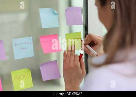 Kreatives Brainstorming entfaltet sich mit farbenfrohen Haftnotizen auf einer Glasplatte in einem hellen Arbeitsbereich Stockfoto
