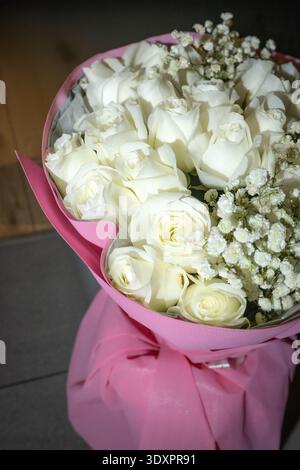 Eleganter weißer Rosenstrauß mit Gypsophila auf dunklem Hintergrund Stockfoto