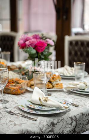 Eleganter Tisch mit rosafarbenen Rosen und Vorspeisen Stockfoto
