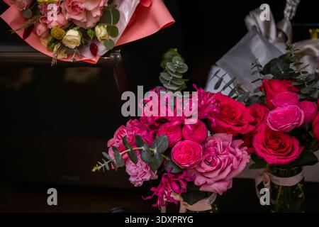 Leuchtendes rosafarbenes Rosen- und Pfingstrosen-Bouquet auf dunklem Hintergrund Stockfoto