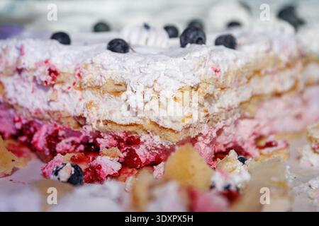 Eine Makroansicht eines feuchten Biskuittortes mit rosafarbener Beerenfüllung und weißer Creme. Stockfoto
