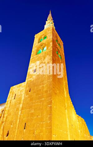 Der hohe Steinturm einer Moschee steht in Damaskus unter einem klaren Nachthimmel. Er ist beleuchtet und zeigt sein Design und seine Struktur. Stockfoto