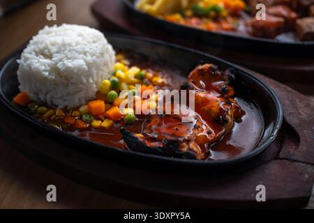 Gegrilltes Hühnchen mit Soße, weißem Reis und Gemüse auf einer heißen Platte Stockfoto