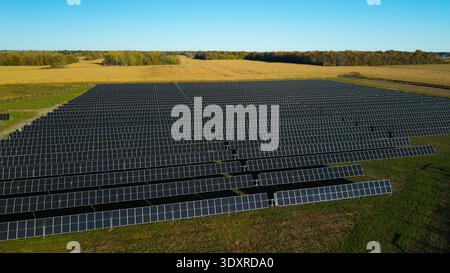 Drohnenansicht eines großen Solarkraftwerks mit Reihen von Photovoltaik-Panels in ländlicher Landschaft Stockfoto