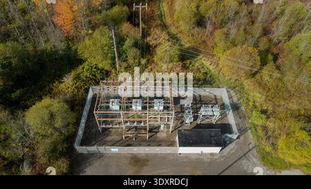 Luftaufnahme eines elektrischen Unterwerks mit Leistungstransformatoren und Übertragungsleitungen in Waldlandschaften Stockfoto