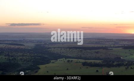 Drohnenlandschaft mit Sonnenaufgang über sanften Weidefeldern und ländlichem Ackerland mit Morgenlicht, das das ländliche Gelände beleuchtet. Stockfoto