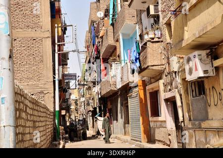 Ein Mann läuft in Luxor, Ägypten, eine enge Wohnstraße mit Backsteinhäusern und Wäscherei entlang Stockfoto