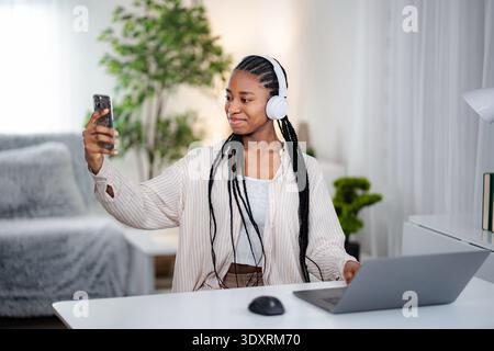 Eine junge Frau, die zu Hause ein Selfie mit Kopfhörern macht Stockfoto