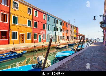 Blick auf die berühmten farbenfrohen Häuser entlang eines Kanals auf Burano Island. Kleine Boote, die unter blauem Himmel im Wasser verankert sind, Lagune Venetian, Veneto, Italien Stockfoto