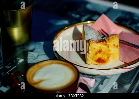 Traditioneller spanischer Käsekuchen mit Cappuccino. Gourmet-Dessert, Kaffeepause am Morgen und gemütliche Café-Atmosphäre. Stockfoto