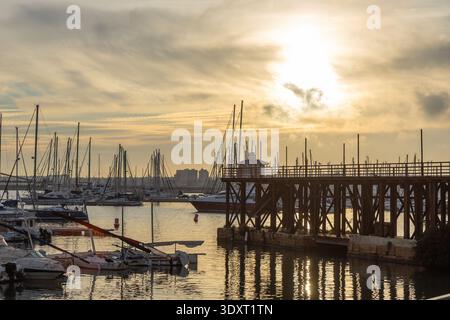 Torrevieja, Spanien - 13. Januar 2026: Eine ruhige Hafenszene zur goldenen Stunde mit zahlreichen Segelbooten, Yachten, einem prominenten Holzpier und Reflect Stockfoto