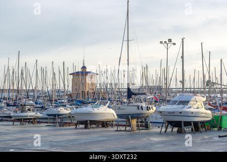 Torrevieja, Spanien - 13. Januar 2026: Eine geschäftige Werft- und Yachtszene mit Trockenbooten, einem Gabelstapler und zahlreichen Yachten im Wasser unter einem bri Stockfoto