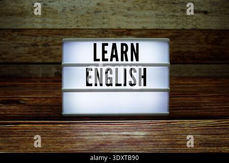 Leuchtkasten mit Text „Learn English“ auf hölzernem Hintergrund Stockfoto