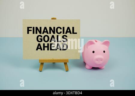 Text „Finanzziele voraus“ auf Papierkarte mit Staffelei und Sparkasse Stockfoto
