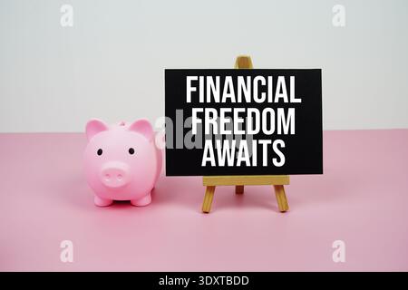 Financial Freedom wartet auf einen Text, der auf Papierkarte mit Staffelei und Sparkasse geschrieben ist Stockfoto