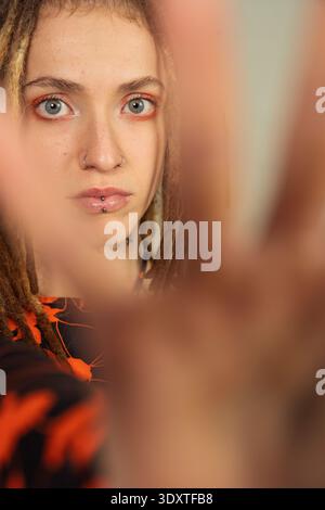 Eine junge Frau mit Dreadlocks und Piercings posiert für ein Porträt und schaut in die Kamera Stockfoto