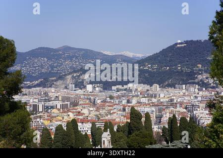 Panoramablick von einem Hügel über Nizzas weitläufige Stadtlandschaft mit Terrakottadächern, dichten Gebäuden und Kiefern Stockfoto