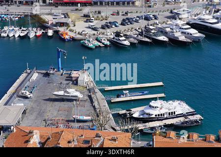 Blick aus der Vogelperspektive auf Nizzas lebhaften alten Hafen mit türkisfarbenem Wasser, Luxusyachten an Betonpiers und farbenfrohen Booten unter Terrakottadächern. Stockfoto