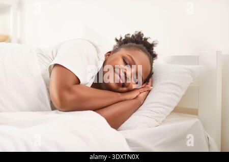 afroamerikanerin schläft gut in einem bequemen Bett, liegt auf weichem Kissen, orthopädischer Matratze Stockfoto