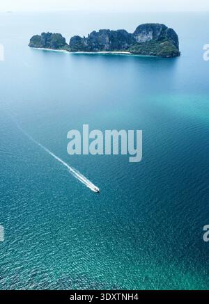 Aus der Vogelperspektive eines Bootes, das durch das türkisfarbene Wasser in Richtung der fernen, zerklüfteten Insel Khao Lak, Phang Nga, Thailand fährt. Stockfoto