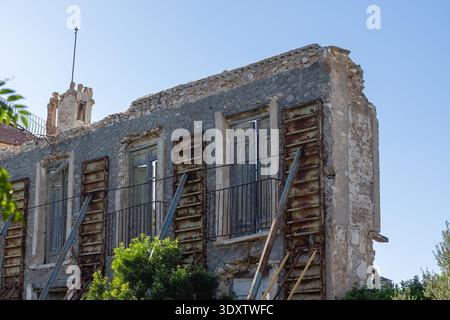 Ein verwittertes Steingebäude in Torrevieja, Spanien, zeigt Anzeichen von Verfall mit rostigem Metallgerüst und kaputten Fenstern, die den zerklüfteten Charme von einfangen Stockfoto