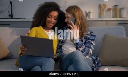 Multiethnische Paare, die zu Hause online mit Laptop kaufen Kaukasischer Mann Afroamerikanerin Kreditkarte sprechen Familie Liebe Ehemann Frau Stockfoto