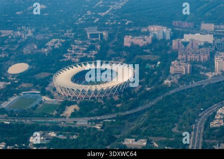 Hochwinkelansicht von Neu-Delhi, die die unverwechselbare Architektur des Jawaharlal Nehru Stadions in einer nebelbedeckten Stadtlandschaft zeigt. Stockfoto