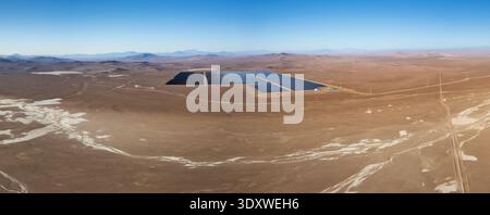 Panorama-Drohnenaufnahme einer großen Solaranlage in der trockenen Landschaft der Atacamawüste unter klarem blauem Himmel. Fantastische Aussicht aus der Luft Stockfoto