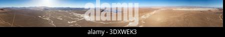 Panoramablick auf das Solarkraftwerk in der riesigen trockenen Landschaft der Atacama-Wüste unter klarem blauem Himmel. Fantastische Luftaufnahme einer Solarenergie-PV-Anlage Stockfoto