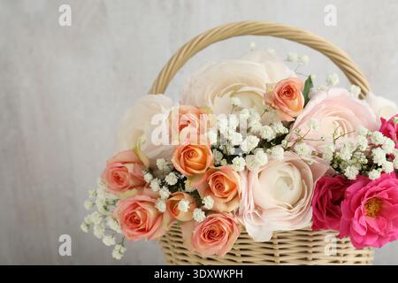 Schöne Blumen im Korb auf hellem Hintergrund, Nahaufnahme. Leerzeichen für Text Stockfoto