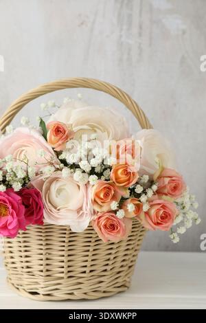 Schöne Blumen im Korb auf weißem Holztisch Stockfoto