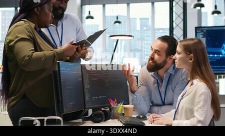 Teamwork-Programmierer entwickeln Softwareanwendungen und arbeiten gemeinsam an der Optimierung von Code. Tech-Startup-Team, das Brainstorming im Büro macht, KI zur Lösung von Engpässen nutzt, Kamera A Stockfoto