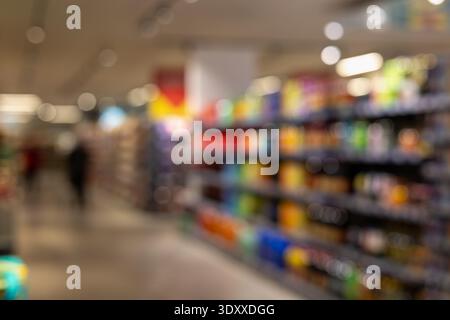 Verschwommener Supermarktgang mit bunten Regalen und weichen Bokeh-Lichtern, idealer Hintergrund für Lebensmitteleinkäufe, Einzelhandelsgeschäfte und Konsumkonzepte Stockfoto