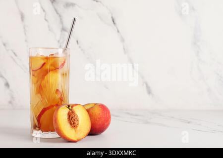 Glas leckerer Pfirsicheistee auf Marmorhintergrund, Nahaufnahme Stockfoto