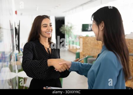 Positive Managerin aus dem Nahen Osten, die dem Geschäftspartner den Handschlag gibt Stockfoto