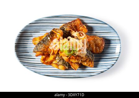 Blick von oben auf die frittierte japanische Makrele in süß-saurer Essigsauce auf einem gestreiften Teller, isoliert auf weißem Hintergrund Stockfoto