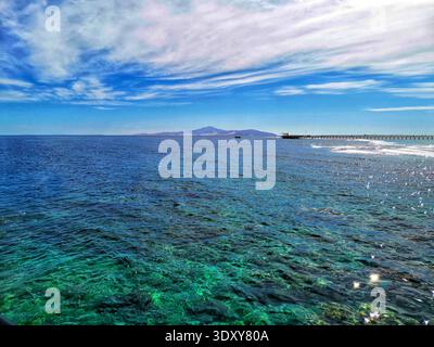 Horizont-Linie von Meer und Himmel. Smaragdgrüne Wasseroberfläche. Blick auf eine Insel in der Ferne. Ein klarer, sonniger Sommertag Stockfoto