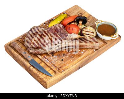 Gegrilltes Rindersteak, serviert mit gegrilltem Gemüse und Dippsoße auf einem Holzbrett. Isoliert auf weißem Hintergrund, Draufsicht. Stockfoto